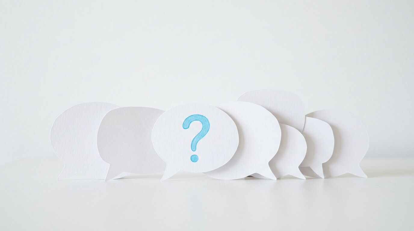 Papier-Sprechblasen auf weißem Grund, die mittlere mit einem blauen Fragezeichen