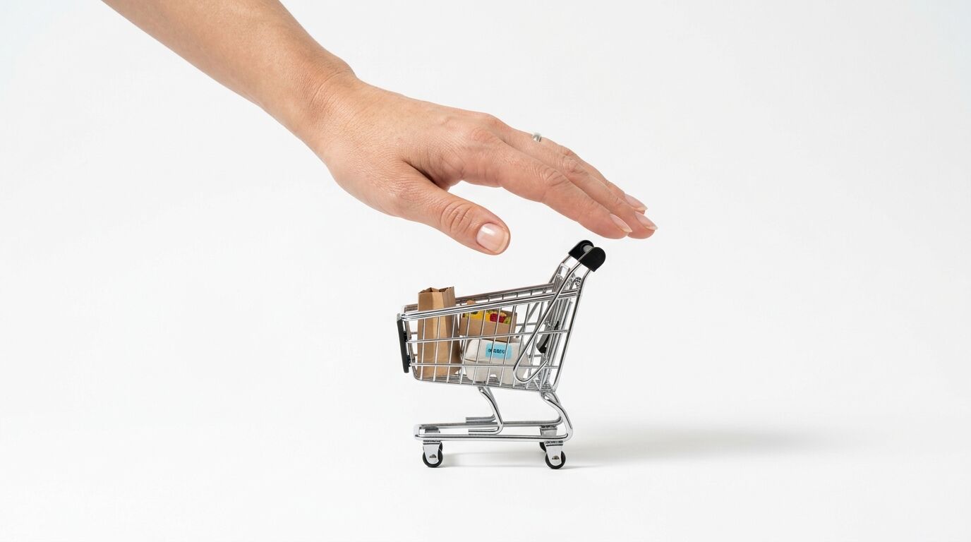 Eine Hand schwebt schützend über einem gefüllten Miniatur-Einkaufswagen