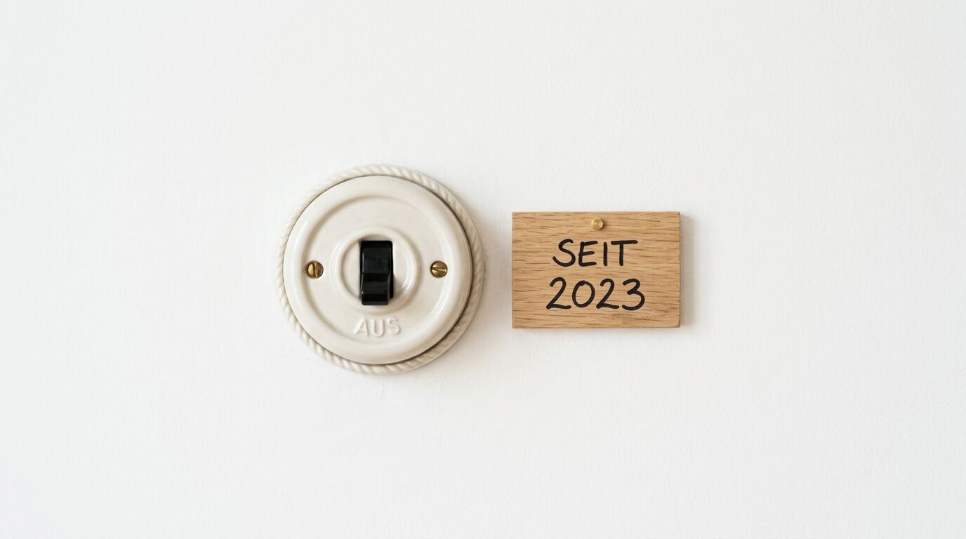 Lichtschalter aus Porzellan in AUS-Stellung mit einem Holzschild daneben, auf dem SEIT 2023 steht