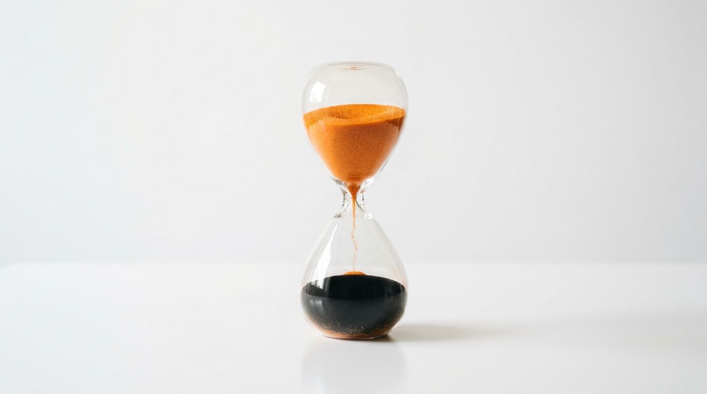 Eine Sanduhr mit orangefarbenem Sand oben und schwarzem unten, freigestellt auf Weiß