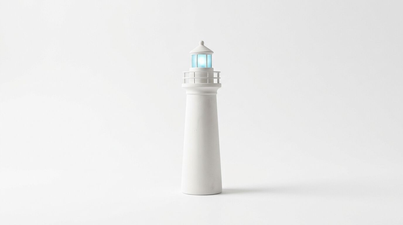 Ein weißer Modell-Leuchtturm mit einem leuchtend blauen Glasaufsatz steht mittig auf weißem Grund