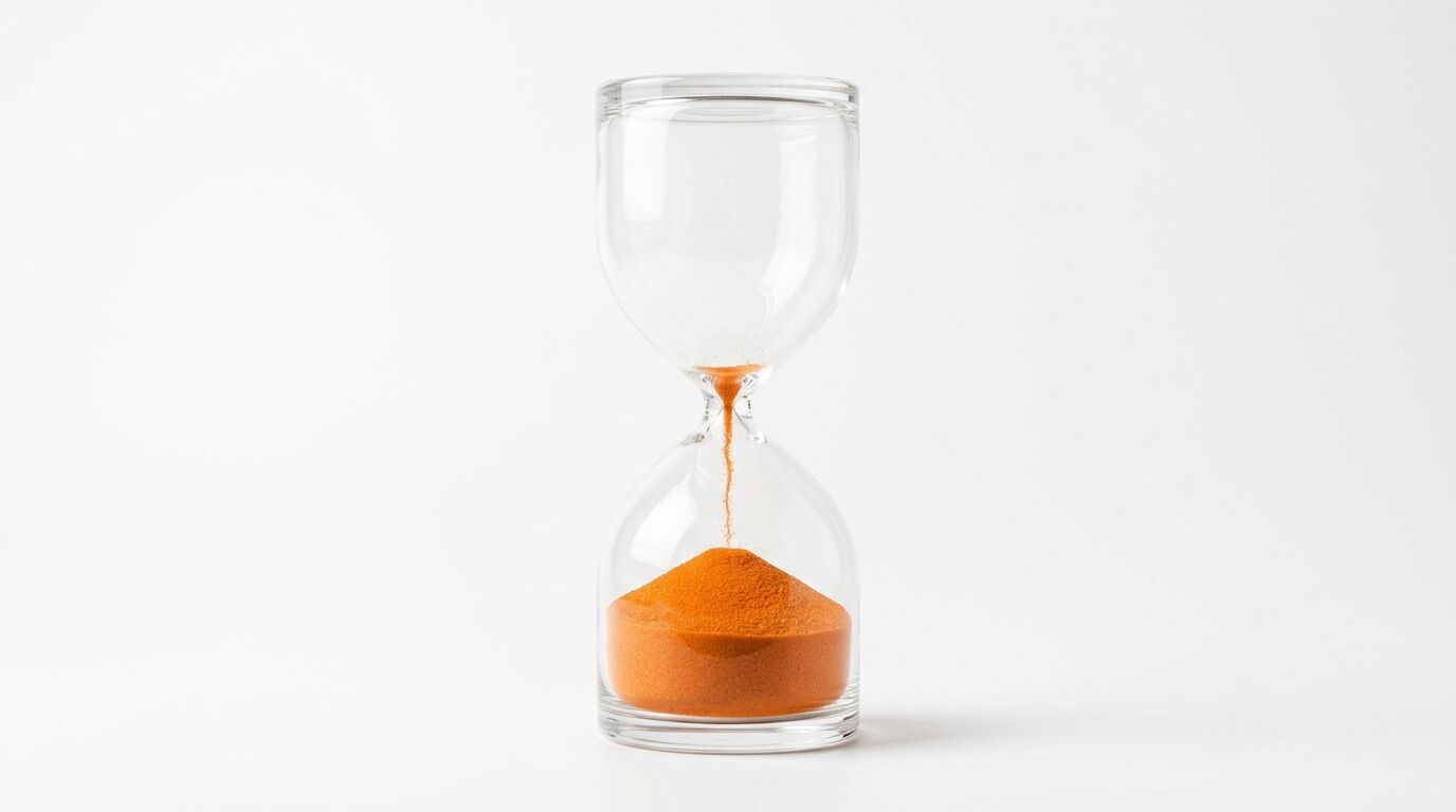 Eine gläserne Sanduhr mit orangerotem Sand auf weißem Hintergrund