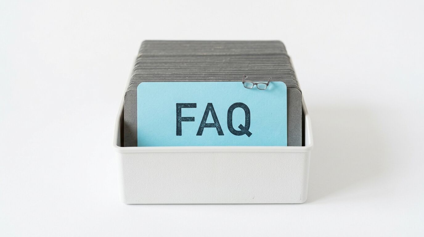 Ein Karteikasten mit einer blauen Karte, auf der „FAQ“ steht und eine Brille steckt