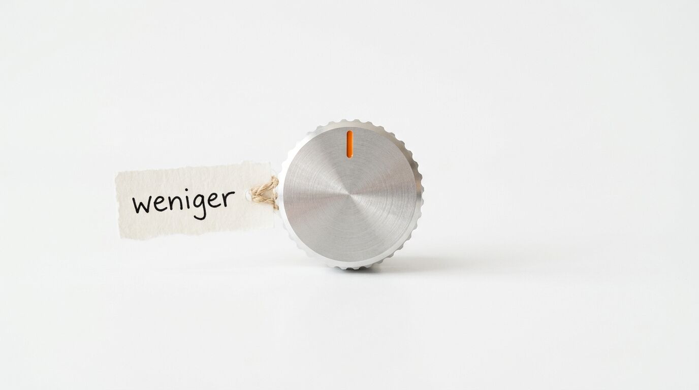 Silberner Drehknopf und Anhänger mit dem Wort „weniger“ auf weißem Hintergrund
