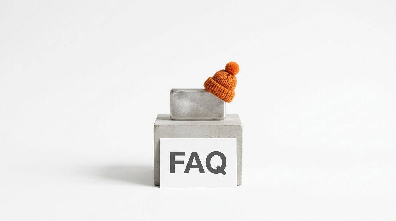 Text „FAQ“ vor Betonsockel, darauf kleinerer Block mit oranger Wollmütze, weißer Hintergrund